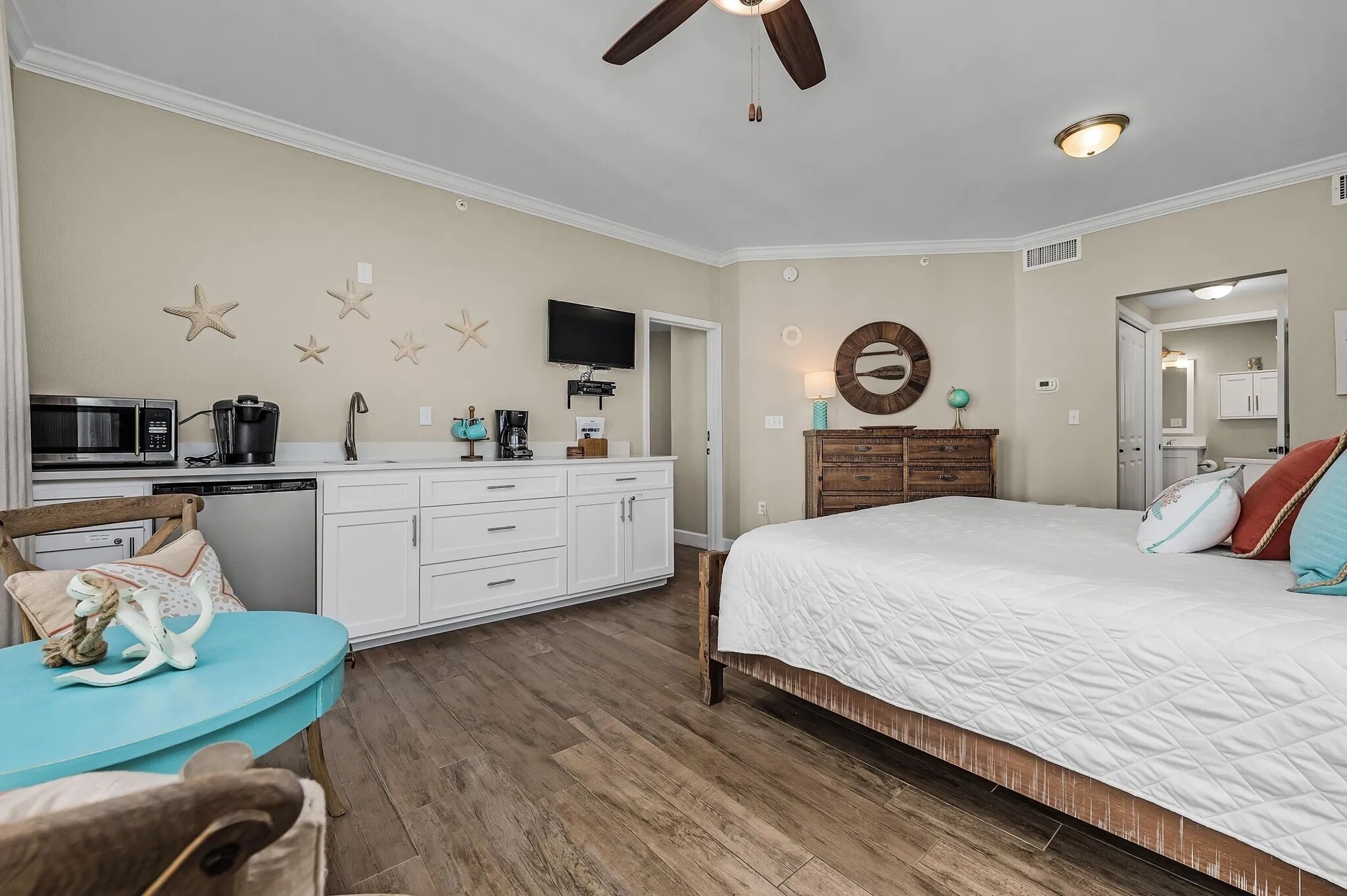 Une chambre comprenant un lit, un bureau avec une chaise, une télévision et un coin cuisine.