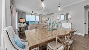 A dining area with a wooden table, chairs, and hanging pendant lights. - Beautiful 5 Star Condo right on the Beach!  Breathtaking Views!! (Navarre Beach)