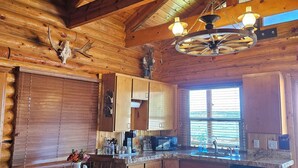Une cuisine rustique avec des poutres en bois, un lustre et un crâne de cerf accroché au mur.