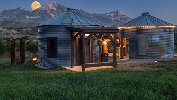 A rustic cabin with a metal roof, a wooden porch, and a small fire pit. - Taylor`s Depot Cabin (Paonia)