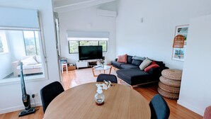 Un salon moderne avec un canapé, un téléviseur et une table à manger avec des chaises.