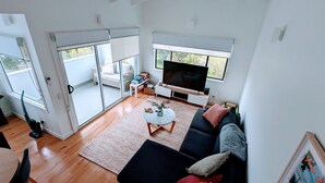 Un salon spacieux avec une grande télévision, un canapé et une table basse.
