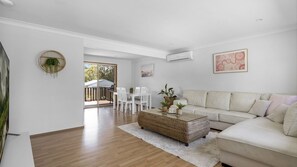 Relax in this stylish living room with a large sofa, coffee table, and dining area, leading to an outdoor patio.