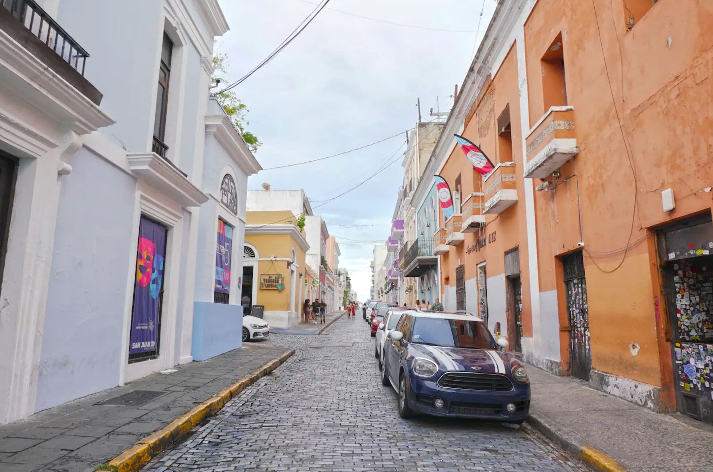 Una calle adoquinada bordeada de edificios coloridos, algunos con balcones y letreros.