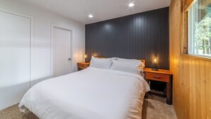 A bedroom with a bed, two bedside tables, a wooden headboard, and a window. - Remodeled Mid-Town Beauty with Spa Retreat 547 (Mammoth Lakes)