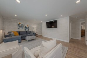 A modern living room with a grey sectional sofa, a white armchair, and a patterned rug.