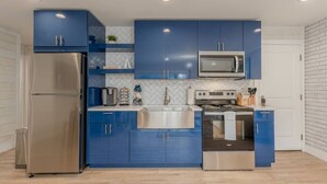 Une cuisine moderne avec des armoires bleues, des appareils en acier inoxydable et un dosseret de carrelage blanc.