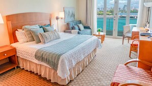 A hotel room with a large bed, a sofa, a desk, and a view of the water. - Mesmerizing Ocean View King Bed Near Beaches (San Juan)