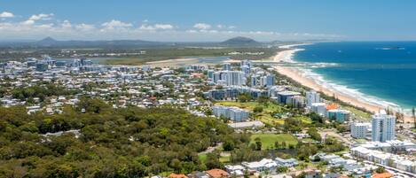 An aerial view of a coastal city with dense residential areas, beachfront properties, and high-rise buildings.