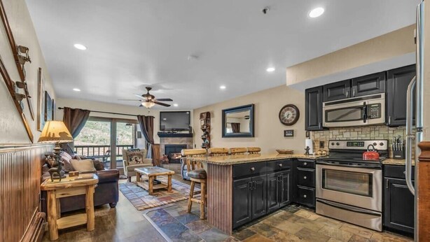 A modern kitchen with dark cabinetry, a large island, and a built-in microwave. - 1BR Ski in Ski Out Steps to Lifts (Park City)