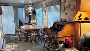 A dining area with a wooden table and chairs, a kitchen area with a stove, and a living room with a leather couch. - 2 bedroom cabin in mineral (Mineral)