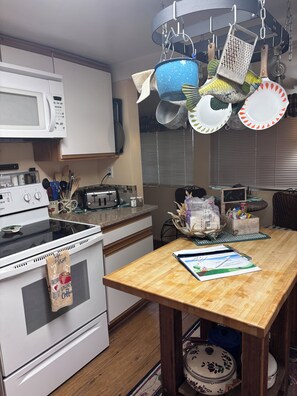A kitchen with white appliances, a wooden table, and hanging pots. -  2 Bedroom rustic cabin in Mineral minutes to entrance of Lassen Park. (Mineral)