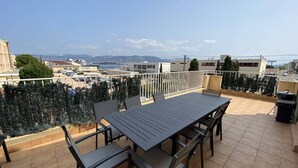 Una terraza en la azotea con una mesa y sillas, vistas de la ciudad y una barandilla.