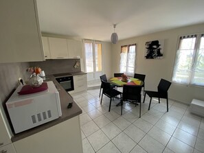 A compact kitchen with a dining area, white cabinets, and a tiled floor.