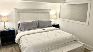 A bedroom with a bed, two bedside tables, a ceiling fan, and a window with blinds. - Beachfront condo with stunning ocean views. Pet-Friendly! (Galveston)