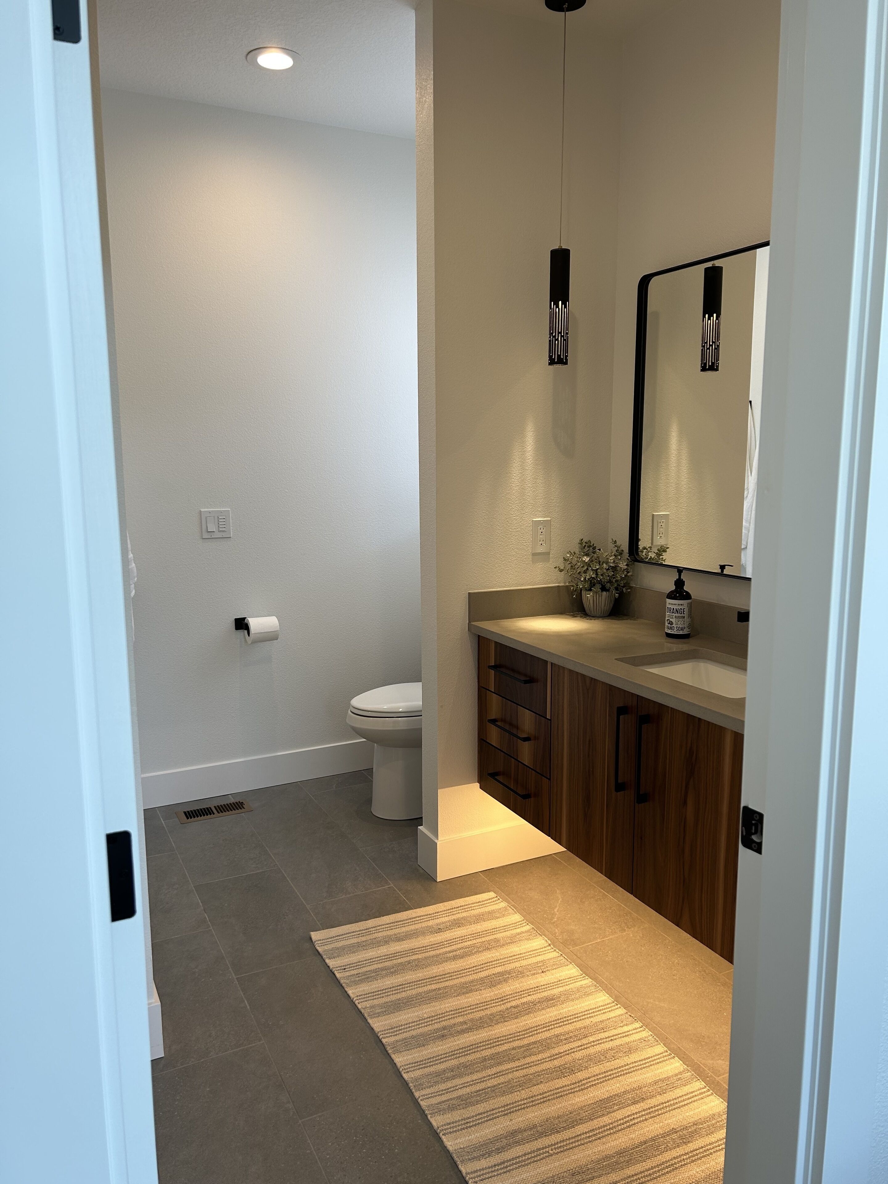 Une salle de bain moderne équipée de toilettes, d’un lavabo, d’un miroir et de meubles en bois.