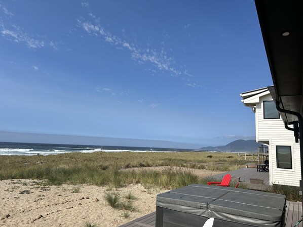 Blick auf einen Strand mit einem Haus, einer Terrasse und einem roten Stuhl.