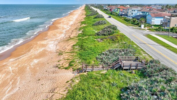 Una carretera costera con una playa a un lado y casas al otro.