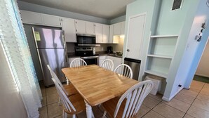 A compact kitchen with white cabinets, a stainless steel refrigerator, a microwave, an oven, and a dishwasher.