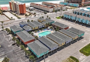 Un hôtel situé en bord de mer, composé de plusieurs bâtiments à étages, doté d’une piscine et d’un parking.