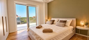 Et soveværelse med en stor seng, en skydedør til en balkon og et natbord med en lampe.