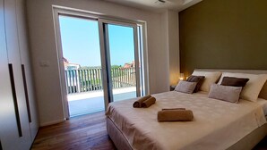 Une chambre avec un grand lit, un balcon et une table de chevet avec une lampe.