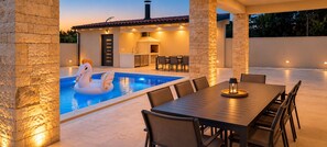An outdoor pool area with a swan float, a dining table, and chairs.
