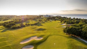 Un parcours de golf avec des bunkers, un drapeau et une vue sur la mer.