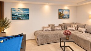Ein Wohnzimmer mit Billardtisch, einer Couch und zwei Bildern an der Wand.