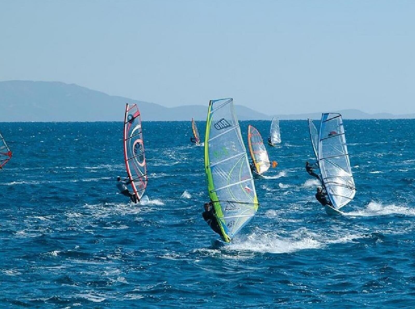 Un grupo de windsurfistas en un día despejado.