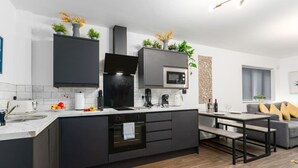 Una cocina moderna con armarios oscuros, una isla central, un microondas y un horno empotrado.