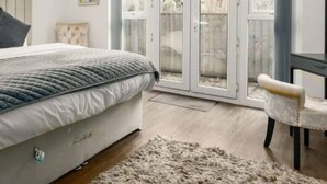 Un dormitorio con cama, una silla, un ventanal con vistas e iluminación en el techo.