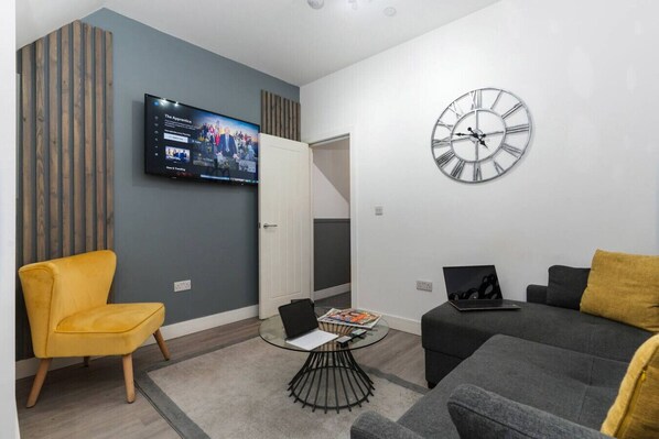 Un salon moderne avec un téléviseur à écran plat, une horloge murale ronde et un canapé.
