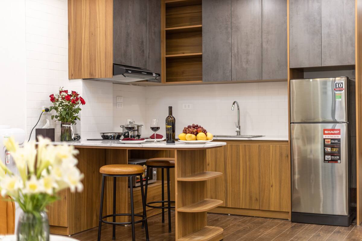 Una cocina moderna con armarios de madera, un refrigerador de acero inoxidable y una isla central con taburetes.