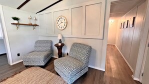 Una habitación con dos sillones estampados, un reloj de pared redondo y suelo de madera.