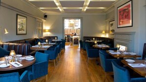 Un restaurante con cabinas y mesas, suelo de madera y un pasillo central.