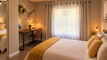 A bedroom with a bed, a desk, a chair, a ceiling fan, and a window with curtains.