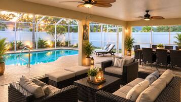 An indoor pool area with wicker furniture, ceiling fans, and a view of the outside.