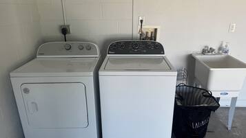Two front-loading washers, a laundry basket, and a sink with a soap dispenser.