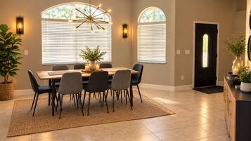A dining area with a table, chairs, a chandelier, and a potted plant.