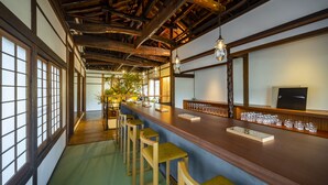 A traditional Japanese-style bar with tatami flooring, wooden beams, and a long counter with stools. - Shisekiryokan Kagetsu Taisyokan (Takeo)