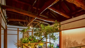 A spacious room with wooden flooring, a glass railing, and a large potted plant. - Shisekiryokan Kagetsu Taisyokan (Takeo)