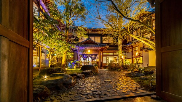 A traditional Japanese garden with a stone pathway, lanterns, and a wooden building. - Shisekiryokan Kagetsu Taisyokan (Takeo)