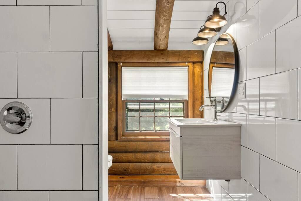 A modern bathroom with a wooden ceiling, a large window, and a white sink.