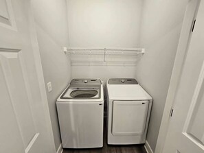 A compact laundry room with two front-loading washing machines and a metal shelf above them. - Mtn Paradise Lake view Indoor/Outdoor pools/2 splash pads, Silver Dollar City (Branson)