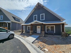 A two-story house with a dark blue exterior, a front porch with stone pillars, and a car parked in front. - Mtn Paradise Lake view Indoor/Outdoor pools/2 splash pads, Silver Dollar City (Branson)