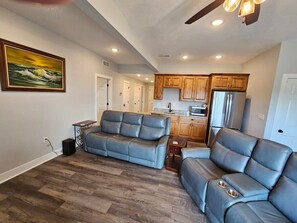 A spacious living area with a sofa, a kitchen in the background, and a painting on the wall. - Mtn Paradise Lake View Heated Indoor Pool Splashpad (Branson)