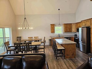 Une cuisine spacieuse avec des meubles en bois, un grand îlot central et un coin repas doté de sièges en cuir.
