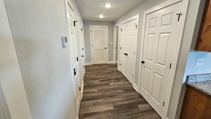 A hallway with white doors, a wooden floor, and a light switch on the wall. - Mtn Paradise Lake view Indoor/Outdoor pools/2 splash pads, Silver Dollar City (Branson)