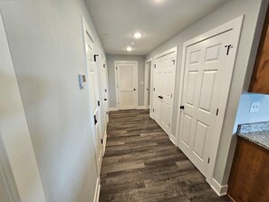A hallway with white doors, a wooden floor, and a light switch on the wall. - Mtn Paradise Lake view Indoor/Outdoor pools/2 splash pads, Silver Dollar City (Branson)